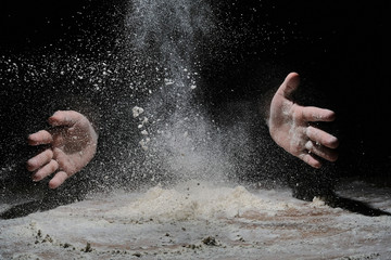 hands flapping flour in the dark. the flour is flying