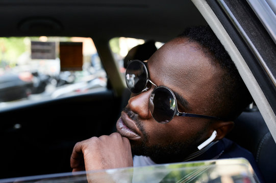Black afro businessman listen music backseat taxi.