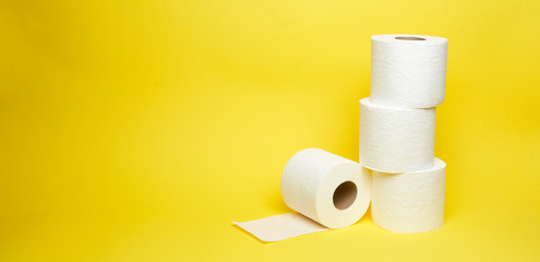 Wide shot of white toilet paper rolls on minimalistic yellow background