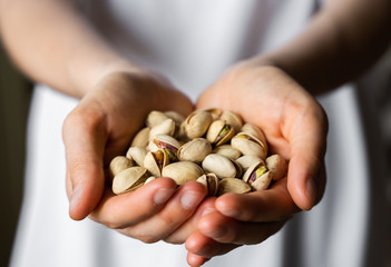 Pistachio in a womans hands. Pistachio nuts is a healthy vegetarian protein and nutritious food. Nuts in a humans hand.