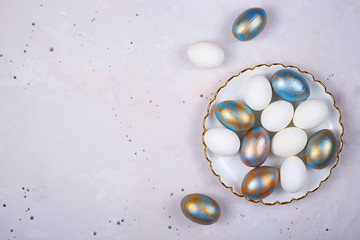 Colored Easter eggs in blue and gold lie on gray background. Minimalistic holiday layout. Top view.