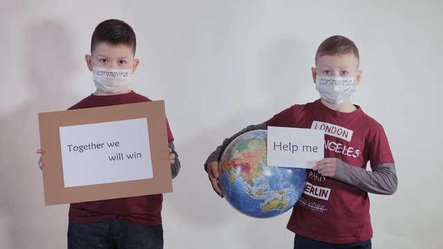 Boy holds a globe, a model of the planet Earth. Child is holding a sign with the inscription: HELP ME, TOGETHER WE WILL WIN. Boy is careful of the virus. Pandemic March 2020. Coronavirus.