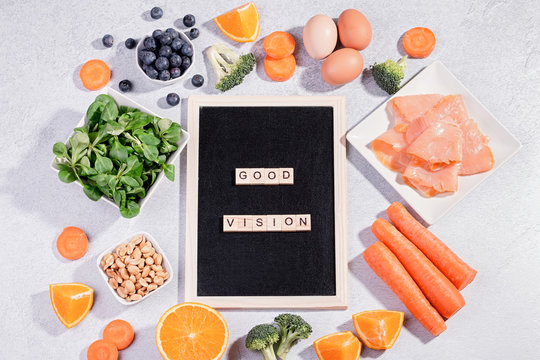Foods that help maintain eyes healthy, products for keeping good vision. Black board with copy space, assortment of food for eye health on concrete background, flat lay, top view