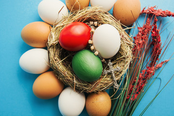 Wishes for Happy Easter holiday card in Italian, Easter eggs as the color of the Italy flag in nest on blue