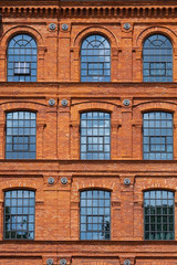 Fototapeta na wymiar Red brick classic industrial building facade with multiple windows background.