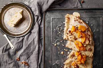 Hot sweet pancakes with peach on old fashioned grey metal tray. Dark backround. Food concept.