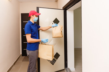 Courier in protective mask and medical gloves delivers takeaway food. Delivery service under quarantine, disease outbreak, coronavirus covid-19 pandemic conditions.