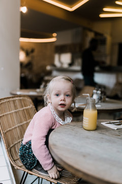 Little girl sitting in a cafe chair waiting for food