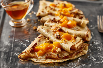 Hot sweet pancakes with peach on old fashioned grey metal tray. Dark backround. Food concept.