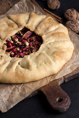 Homemade galette pie with apples, elder berries and walnuts decorated with fresh cowberry