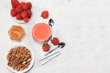 Useful breakfast. Strawberry smoothie, cocktail, granola, fresh berries on a gray concrete background. The concept of healthy and natural food, detox diet, food for children, rustic minimal style.