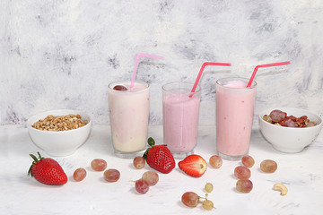 Useful breakfast. Strawberry smoothie, cocktail, granola, fresh berries and grapes on a gray concrete background. The concept of healthy and natural food, detox diet, food for children,