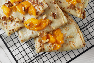 Hot sweet pancakes with peach on wooden table. White backround. Food concept.