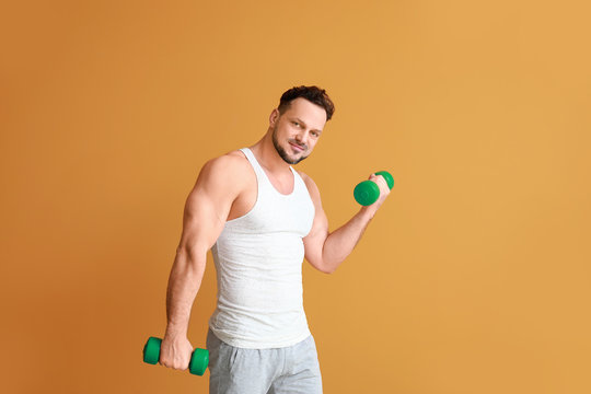 Sporty Man With Dumbbells On Color Background