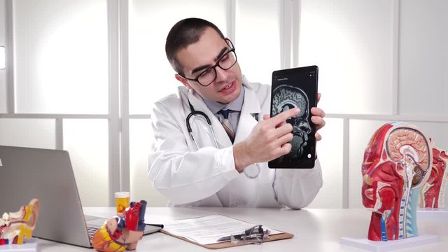 Medical Professional Doctor, discussing the MRI results of a brain scan image showed on his tablet computer device. Public Domain Image