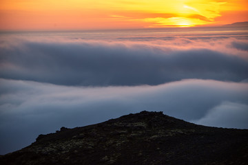 Dreamy misty landscape above the sea of clouds, mountains at sunset in Iceland
