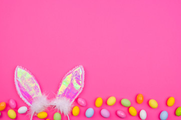  A lot of colored easter eggs, on a pink background. Bunny ears as a symbol of the spring holiday. Happy Easter card with copy space for text. Minimal style. Banner. Long format