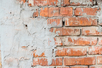Texture of an old broken red brick wall with cement mortar. Background of red clay brick on a broken wall with cement mortar and plaster