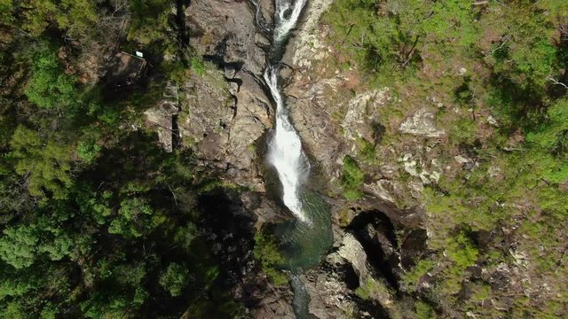 Vertical ascending high over Australian waterfalls in isolated bushland , Drone overhead