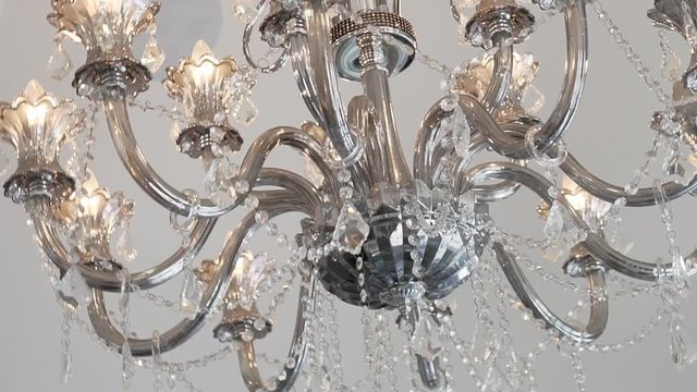 This is a turning shot of a beautiful chandelier hanging from the ceiling of an upscale clothing boutique.