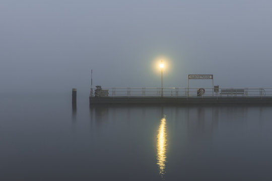 Germany, Hamburg, Outer Alster Lake jetty shrouded in thick fog