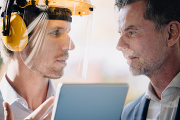 Businessman and man wearing safety helmet facing each other