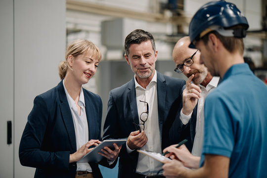 Business people and worker talking in a factory