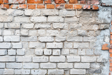 Texture of an old broken wall of white and red brick with cement mortar. Background of clay and silicate brick on a broken wall with a grey shade