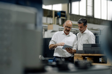 Two businessmen using tablet in a factory