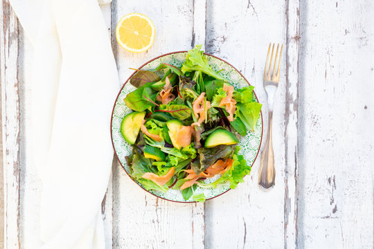 Plate of ready-to-eat green salad with arugula,?Lollo?Rosso?lettuce, baby spinach, beetroot leaves, avocado, corn salad and salmon