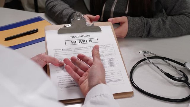 Doctor talking with a patient about a herpes diagnosis. Discussing medical stuff and patient about STD at a desk.
