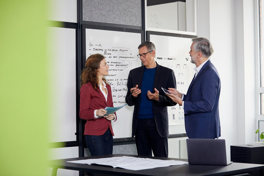 Two businessmen and businesswoman working together on a project in office