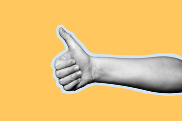 Child hand shows thumb up on yellow background. Paper cut style.