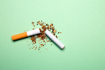 Broken cigarette on a green background, tobacco