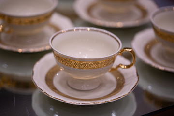 Arrangement of a luxury porcelain dinnerware with golden hand painted. Interior element. Setting of a classy dining table with luxury porcelain. Luxury antique style golden dinner set.	