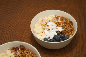 Handmade Bowl healthy tasty breakfast of yogurt, smoothie with granola, nuts, bananas and berries