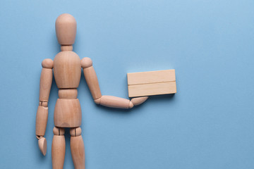 Wooden two blocks holds a mannequin on a blue background.