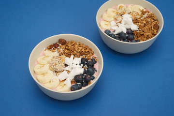Handmade Bowl healthy tasty breakfast of yogurt, smoothie with granola, nuts, bananas and berries