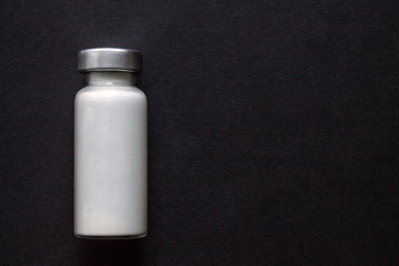 Glass ampoule with white medicine close up on a black background with copy space
