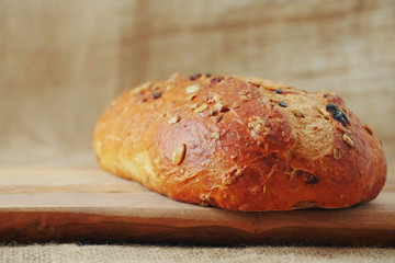 Fresh sourdough loaf bread with cranberry and sunflower seeds on a wooden board and hessian table cloth. Bakery product.