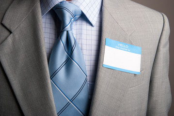 Close-up of a blank name tag stuck to the lapel of the suit of an unrecognizable businessman