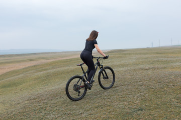Girl on a mountain bike on offroad, beautiful portrait of a cyclist in rainy weather, Fitness girl rides a modern carbon fiber mountain bike in sportswear. Close-up portrait of a girl in red bandana.