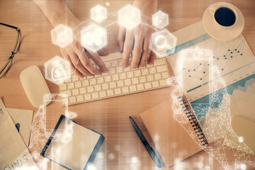 Double exposure of man's hands typing over computer keyboard and tech theme hologram drawing. Top view. Technology concept.