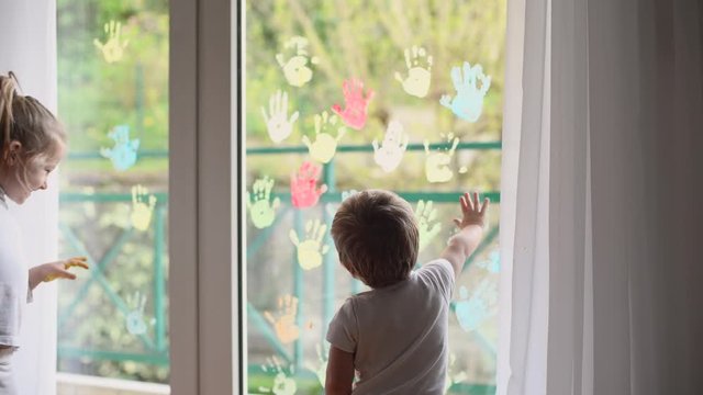 Children paint with palms on the window. Quarantine Stay at home