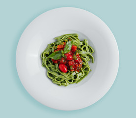 Spaghetti pasta with homemade spinach sauce, green spaghetti, fried tomatoes and fresh basil leaves, vegetarian foodclose-up on a white background . top. view from above