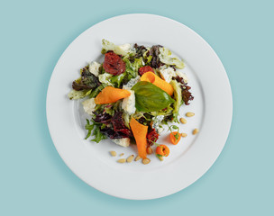salad with sun-dried tomatoes, cabbage leaves, carrot slices Dor Blue cheese on a white plate, top view, top