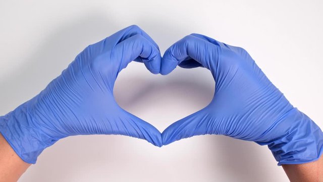 Hands of a doctor or nurse in medical gloves depict a heart on a white background, caring doctor and medicine concept.