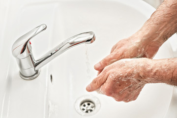 Senior elderly man his hands with soap under tap water faucet, detail photo. Can be used as hygiene illustration concept during coronavirus / covid-19 outbreak prevention