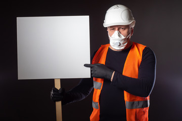 Builder demonstrates a white banner. A worker in a respirator protests against a reduction....