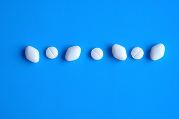  white pills in a row on blue background 